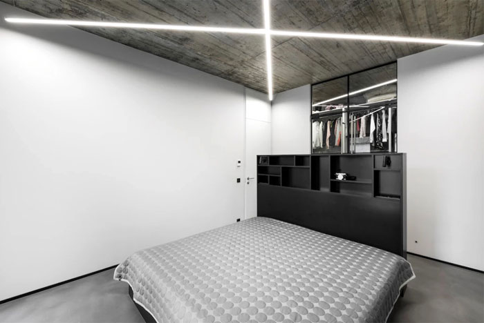 Открытые бетонные потолки с неоновым освещением и черные акценты в интерьере стильных апартаментов